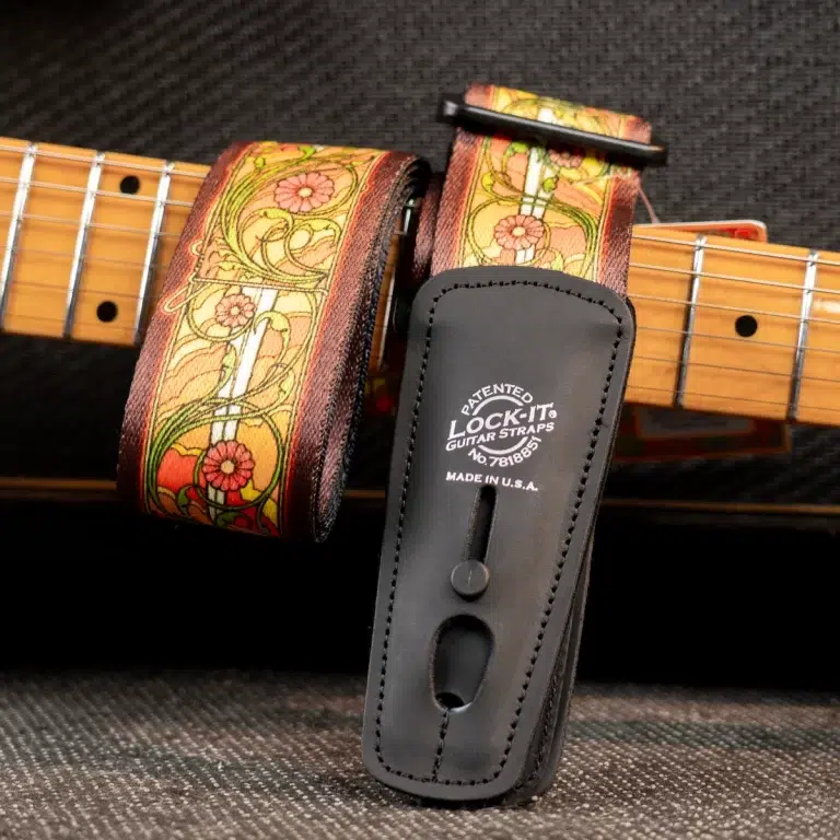 Floral-patterned leather guitar strap with brown edges attached to a guitar neck, showing a LOCK-IT strap lock in use. ขายราคาพิเศษ