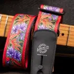 Red floral guitar strap with purple flowers and green leaves, attached to a guitar, featuring a black Lock-It pad. ขายราคาพิเศษ