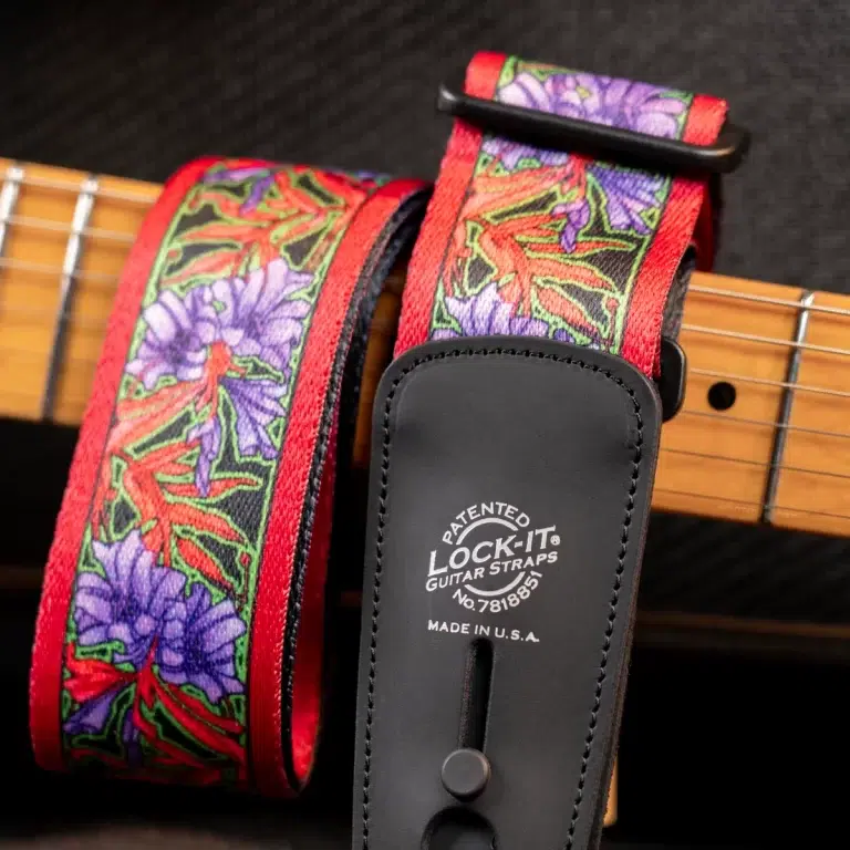 Red floral guitar strap with purple flowers and green leaves, attached to a guitar, featuring a black Lock-It pad. ขายราคาพิเศษ