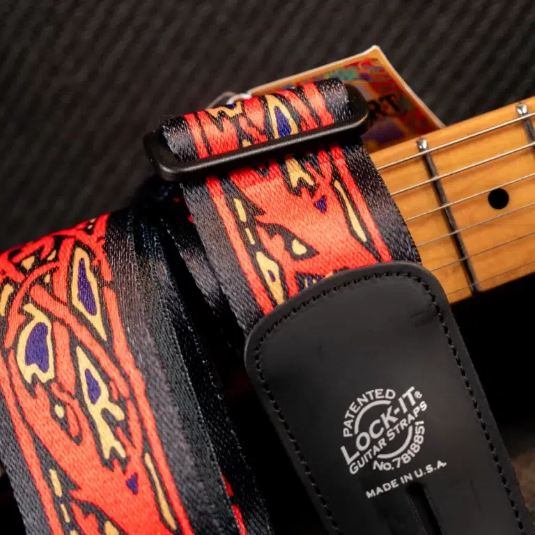 Close-up of a colorful guitar strap with a black leather attachment and a Lock-It guitar strap brand patch showing Made in USA text. ขายราคาพิเศษ