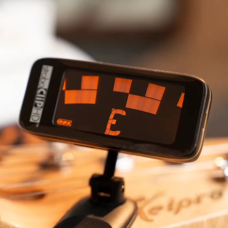 Close-up of a smartphone mounted on a stand, showing an orange geometric display with blocky shapes on the screen. ขายราคาพิเศษ