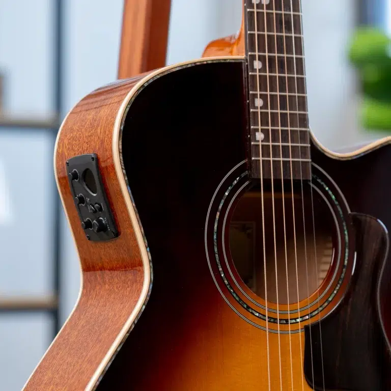Close-up of an acoustic-electric guitar with a sunburst finish, showing the soundhole, strings, and side-mounted control panel. ขายราคาพิเศษ