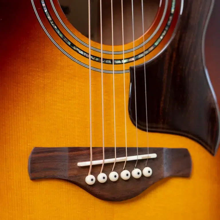 Close-up of an acoustic guitar's body showing strings over the bridge and soundhole. ขายราคาพิเศษ