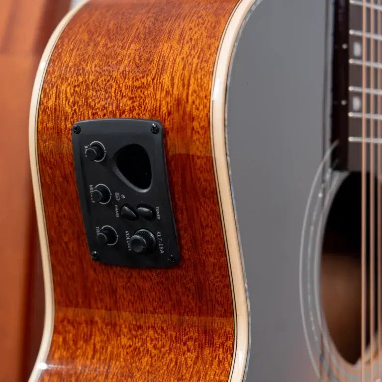 Close-up of a wood-grain acoustic guitar with a black preamp panel and knobs (volume, treble, bass). ขายราคาพิเศษ
