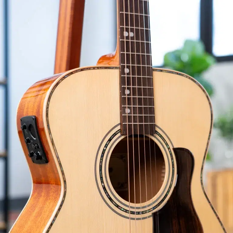 Close-up of an acoustic guitar showing the light wood top, soundhole, and dark fretboard with metal strings. ขายราคาพิเศษ