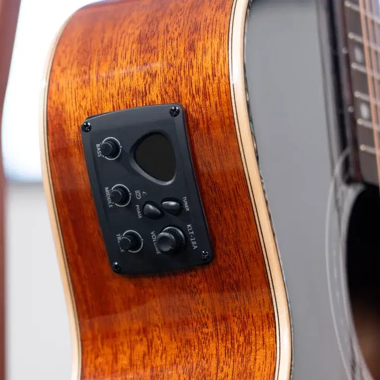 Close-up of an acoustic guitar's side with a black control panel and knobs for volume, bass, middle, phase, and tuner on warm wood. ขายราคาพิเศษ