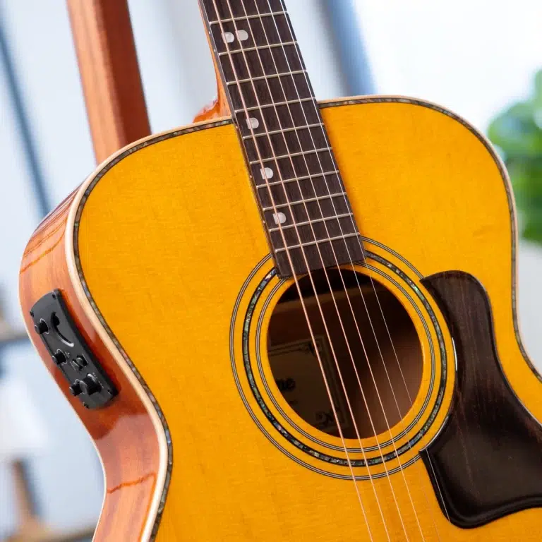 Close-up of a bright yellow acoustic guitar, showing the soundhole, strings, and fretboard detail on the neck. ขายราคาพิเศษ