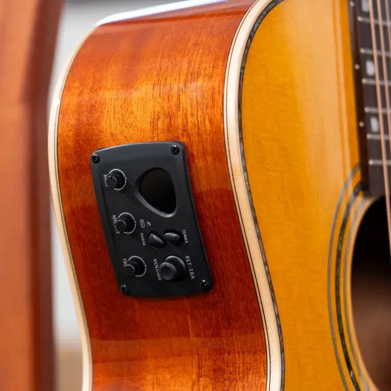 Close-up of an acoustic guitar body with a black pickup control panel mounted on the side. ขายราคาพิเศษ