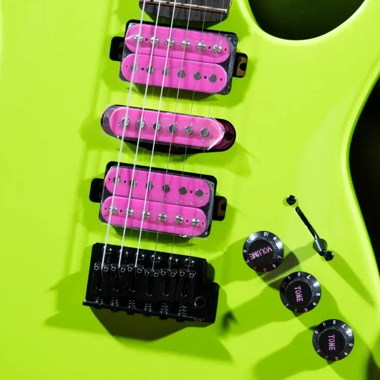 Close-up of a neon lime-green electric guitar, highlighting pink pickups, a black tremolo bridge, and control knobs labeled Tone and Volume. ขายราคาพิเศษ