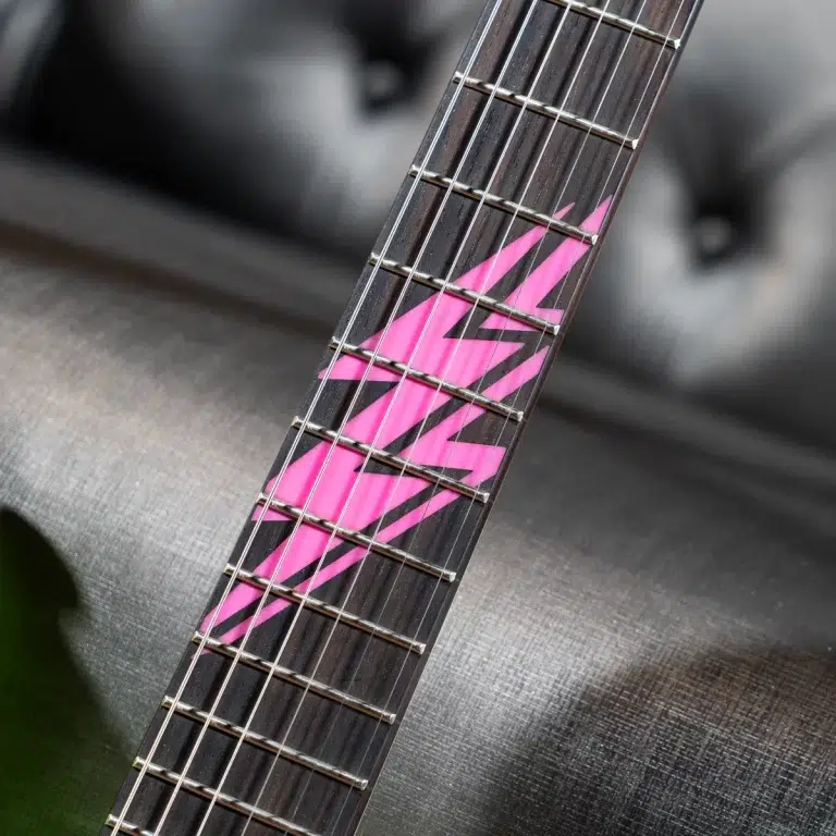 Close-up of a guitar neck with pink geometric zigzag design on the dark fretboard and metal frets. ขายราคาพิเศษ