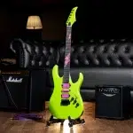Neon-green electric guitar on a wheeled stand in a dim studio, with a Marshall amp and a purple cable on the wooden floor. ขายราคาพิเศษ