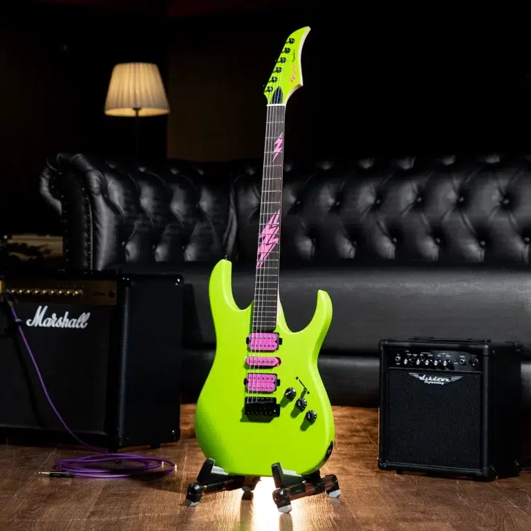Neon-green electric guitar on a wheeled stand in a dim studio, with a Marshall amp and a purple cable on the wooden floor. ขายราคาพิเศษ