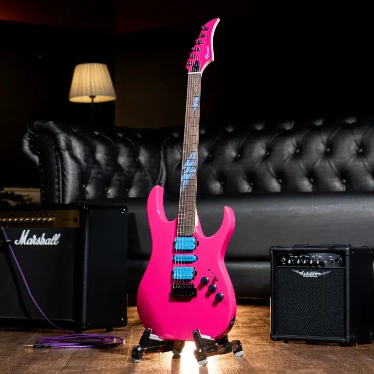Bright pink electric guitar on a stand in a recording studio, with a Marshall amp and purple cable nearby. ขายราคาพิเศษ