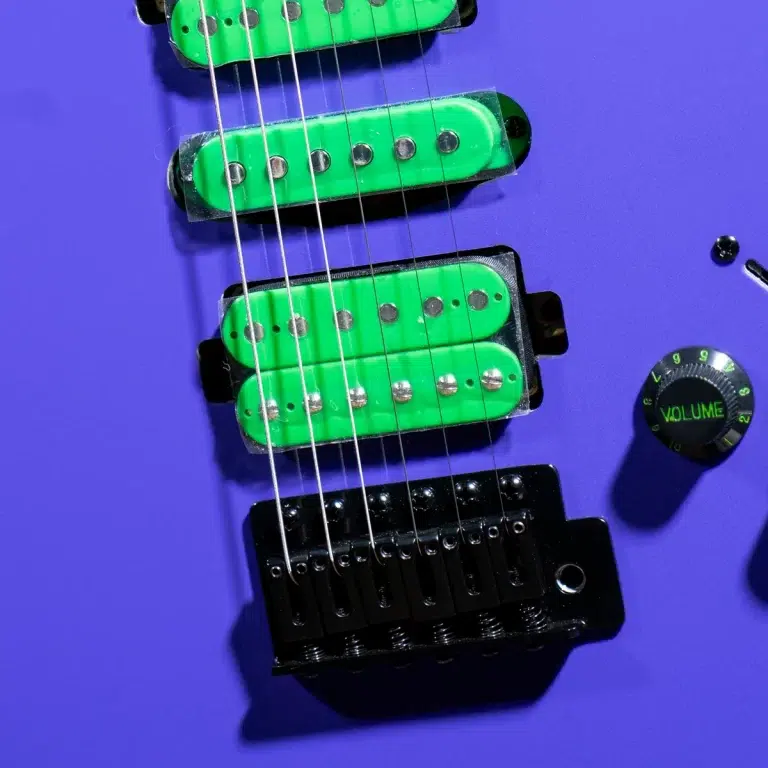 Purple electric guitar body featuring bright green pickups and a black tremolo bridge, with a volume knob nearby ขายราคาพิเศษ