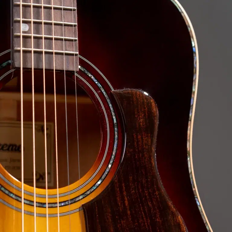 Close-up of an acoustic guitar focusing on the sound hole, strings, and sunburst wooden body with a polished finish. ขายราคาพิเศษ