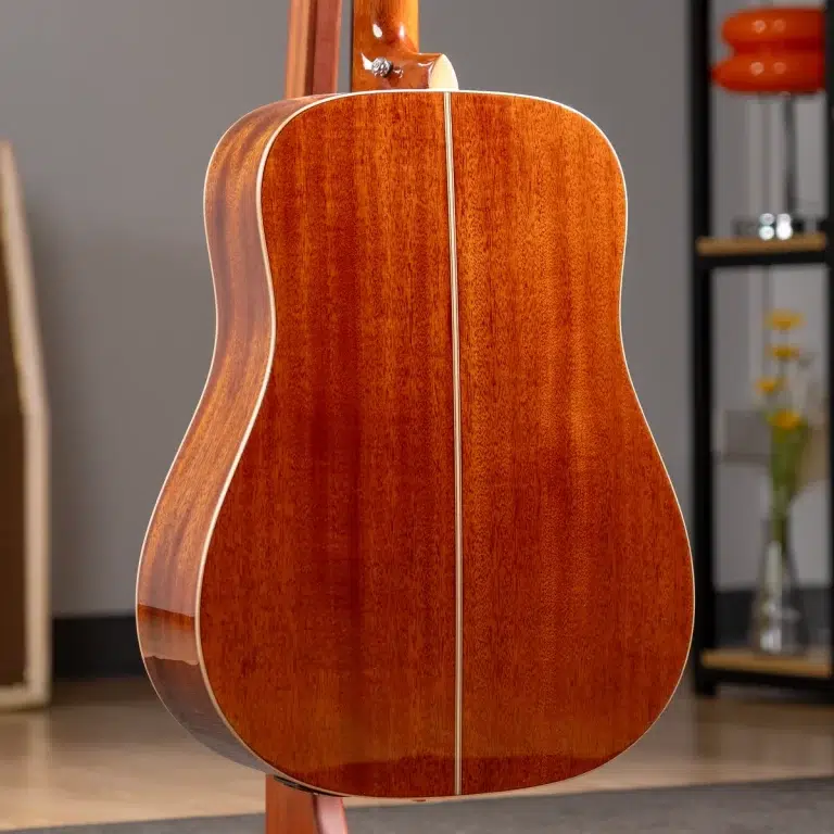 Back view of a polished wooden acoustic guitar showing a reddish-brown finish and a light center seam. ขายราคาพิเศษ