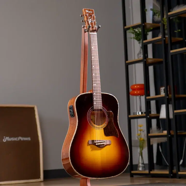 Sunburst acoustic guitar on a stand in a home studio with a shelving unit in the background. ขายราคาพิเศษ
