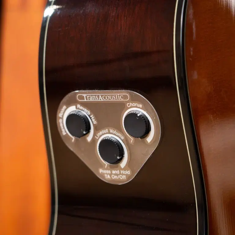 Close-up of a TransAcoustic guitar control panel with three knobs for Reverb/Hall, Chorus, and Lineout Volume on a glossy dark body. ขายราคาพิเศษ