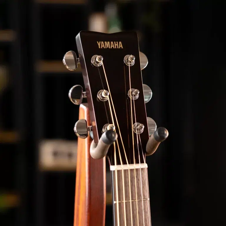 Close-up of a Yamaha acoustic guitar headstock with tuning pegs and strings visible against a dark background, logo readable ขายราคาพิเศษ