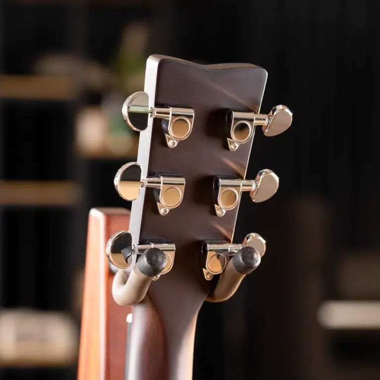 Close-up of a guitar headstock with six chrome tuning pegs on a dark wood neck, blurred background. ขายราคาพิเศษ