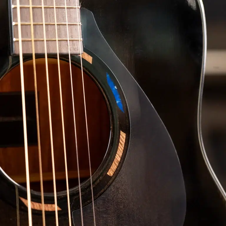 Close-up of a black acoustic guitar showing strings over the sound hole and part of the fretboard. ขายราคาพิเศษ