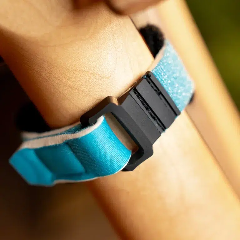 Close-up of a blue fabric strap with a black plastic buckle secured around a person's shoulder/neck area. ขายราคาพิเศษ