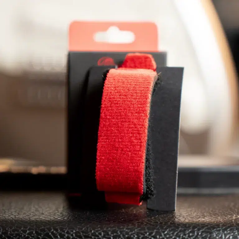 Close-up of a red Velcro strap on a black plastic mount, part of product packaging. ขายราคาพิเศษ