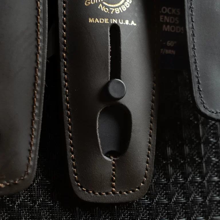 Close-up of a black leather gun holster with visible stitching and a portion of a firearm showing the trigger guard and metal finish, marked 'Made in U.S.A.' ขายราคาพิเศษ