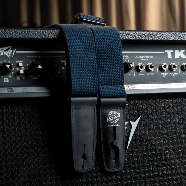 Close-up of a blue woven guitar strap attached to an amplifier, showing strap locks and input panel knobs ขายราคาพิเศษ