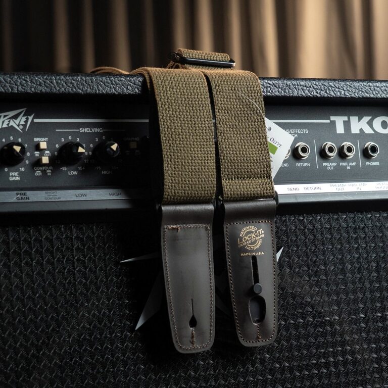 Close-up of a guitar amplifier with two brown leather strap ends and a khaki fabric strap resting over the top. ขายราคาพิเศษ