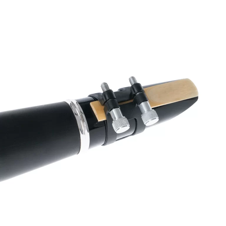 Close-up of a black woodwind mouthpiece with a reed and metal tightening screws on the ligature. ขายราคาพิเศษ