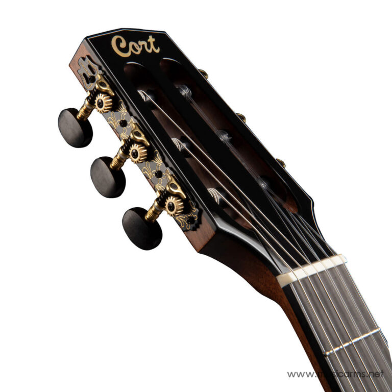 Close-up of a classical guitar headstock with gold filigree, tuning pegs, and strings; brand 'Cort' visible on the headstock. ขายราคาพิเศษ