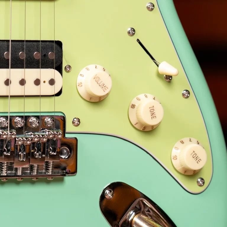 Close-up of a mint-green electric guitar showing volume and tone knobs, pickup, and chrome bridge. ขายราคาพิเศษ
