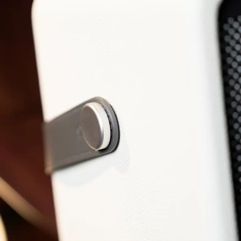 Close-up of a metallic round knob embedded in a white textured panel. ขายราคาพิเศษ