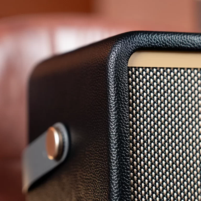 Close-up of a black textured speaker cabinet corner with a woven grille. ขายราคาพิเศษ