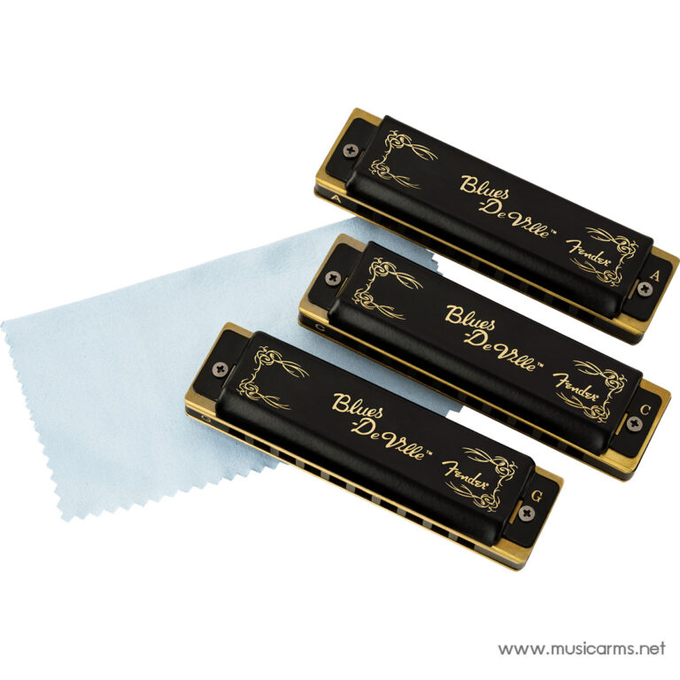 Three Blues DeVille harmonicas with gold edges resting on a pale blue cleaning cloth on a white background, shown from an angled top view. ขายราคาพิเศษ
