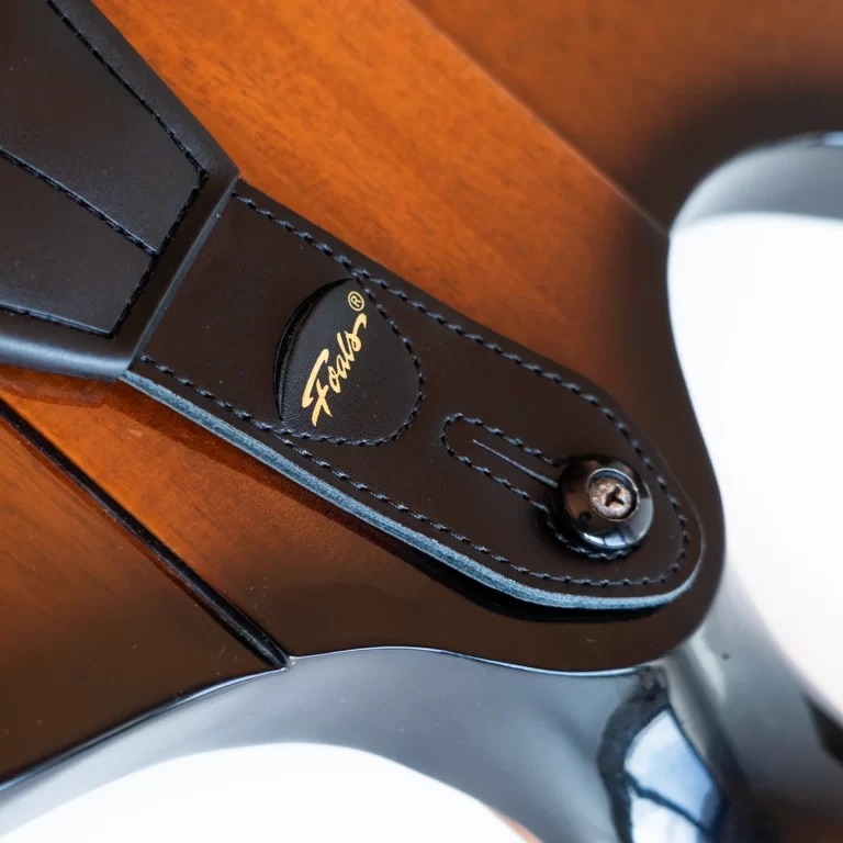 Close-up of a black leather guitar strap with a Fender logo near the body of a sunburst guitar. ขายราคาพิเศษ