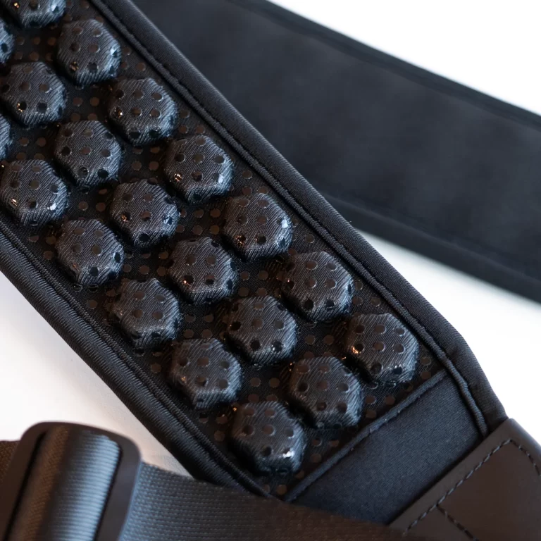 Close-up of a black massager belt with raised, stud-like nodes along the inner surface for acupressure.