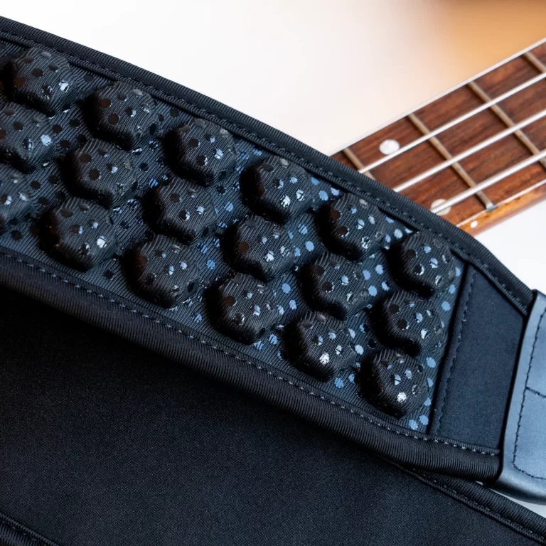 Close-up of a black padded guitar strap with blue-dotted pattern laid across a guitar neck and body edge. ขายราคาพิเศษ