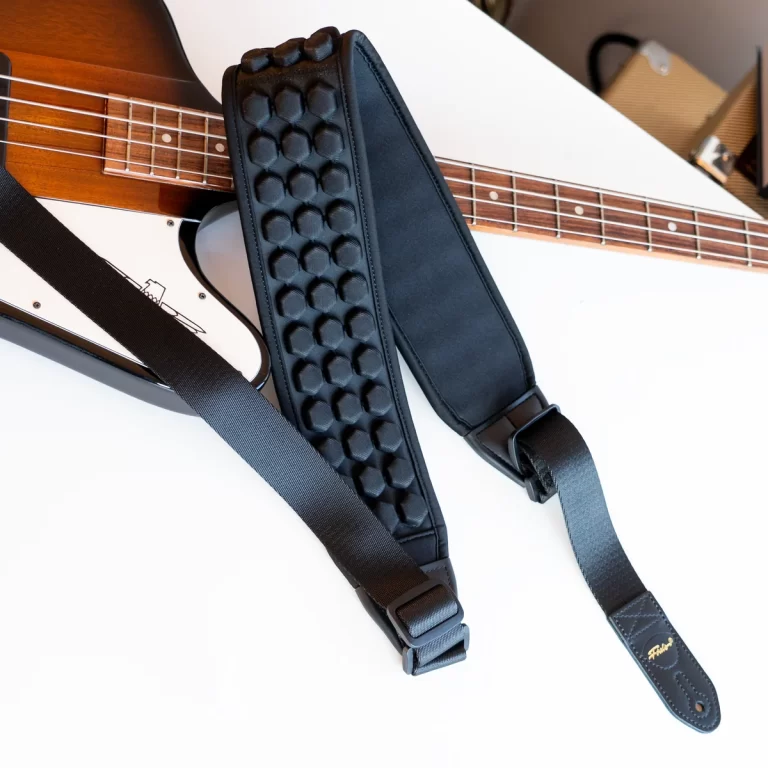Black padded guitar strap with bubble padding laid across a sunburst electric bass guitar with a white body and rosewood fretboard. ขายราคาพิเศษ