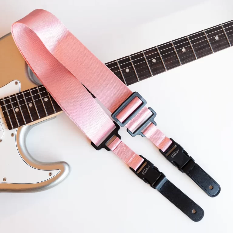 Electric guitar with a light pink strap draped across the body, showcasing dual length straps with black ends and buckles. ขายราคาพิเศษ