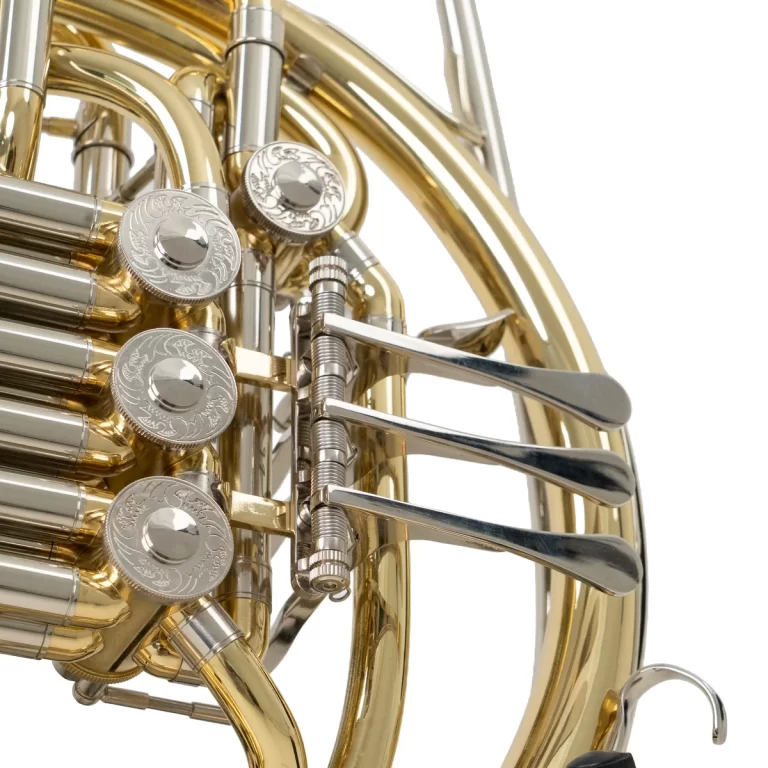 Close-up of a brass French horn's valves and tuning slides, showing shiny silver valve buttons and ornamental engravings. ขายราคาพิเศษ