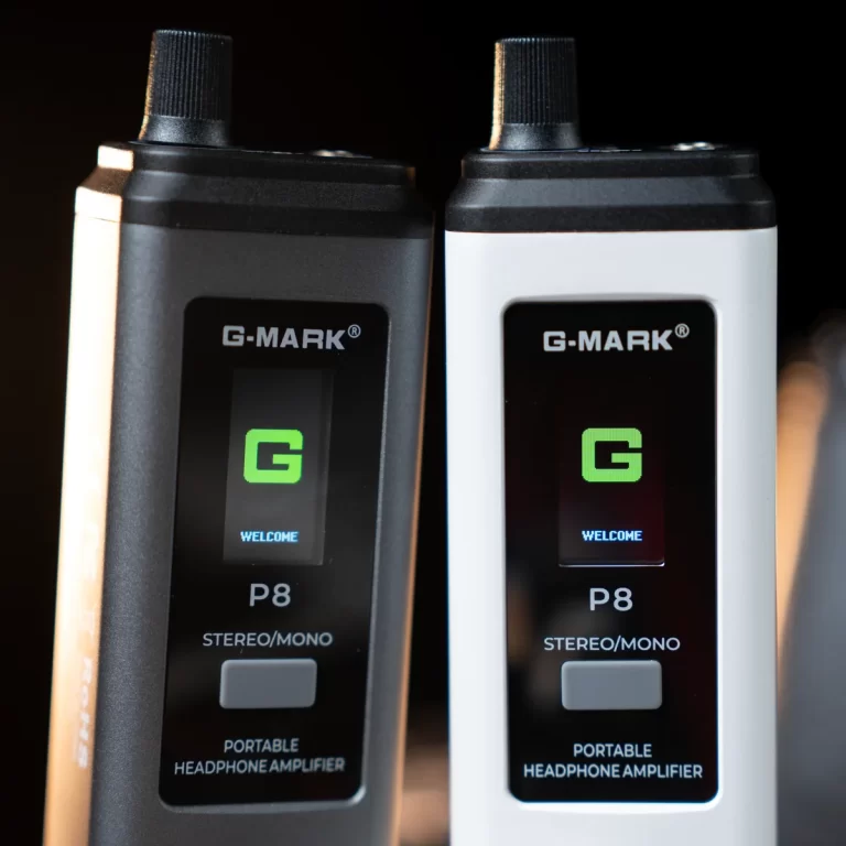 Two G-MARK P8 portable headphone amplifiers side by side, one black and one white, showing their screens with a green 'G' and 'WELCOME' text. ขายราคาพิเศษ