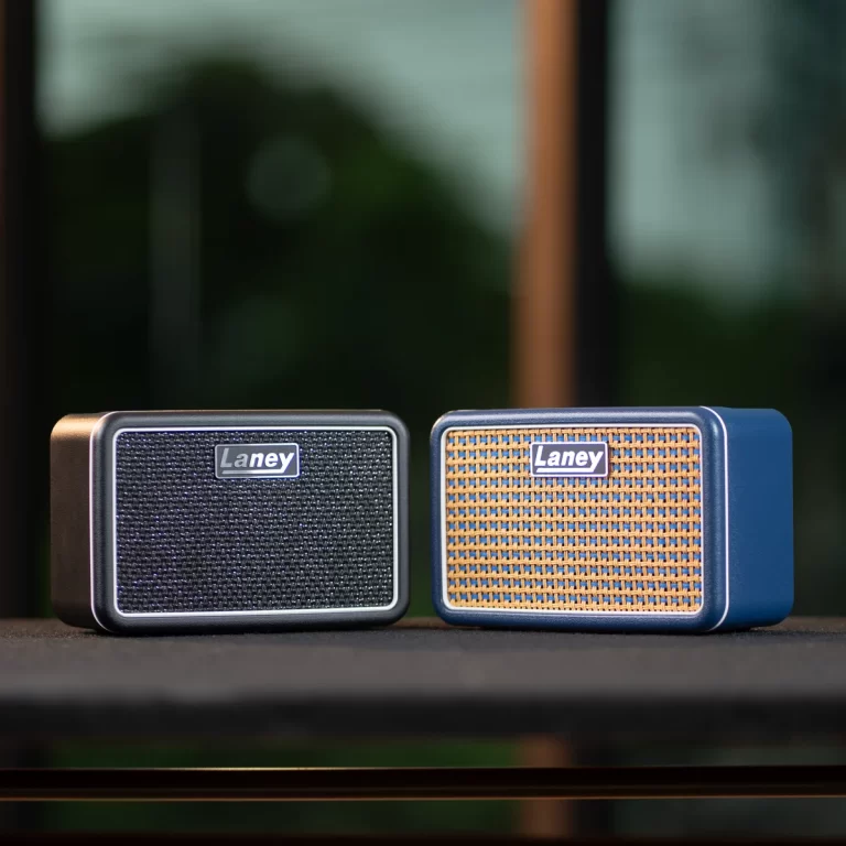 Two Laney portable speakers sit side by side on a table, one with a dark woven grille and the other with a brown woven front and blue casing. ขายราคาพิเศษ