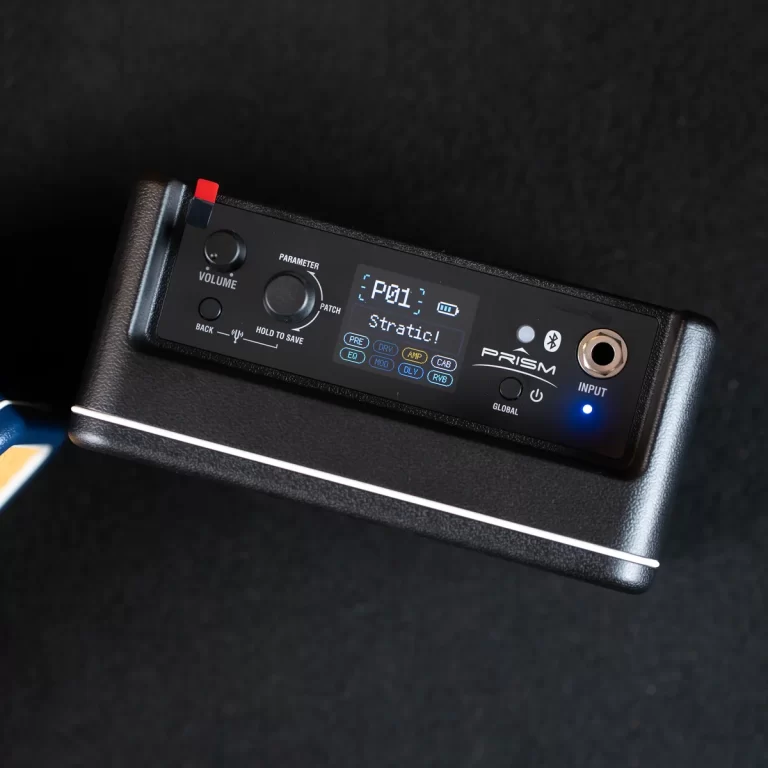 Close-up of a PRISM guitar effects processor on a pedalboard, showing a small display and control knobs on a black panel. ขายราคาพิเศษ