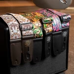Row of colorful patterned guitar straps hanging from a black case, buckles facing forward. ลดราคาพิเศษ