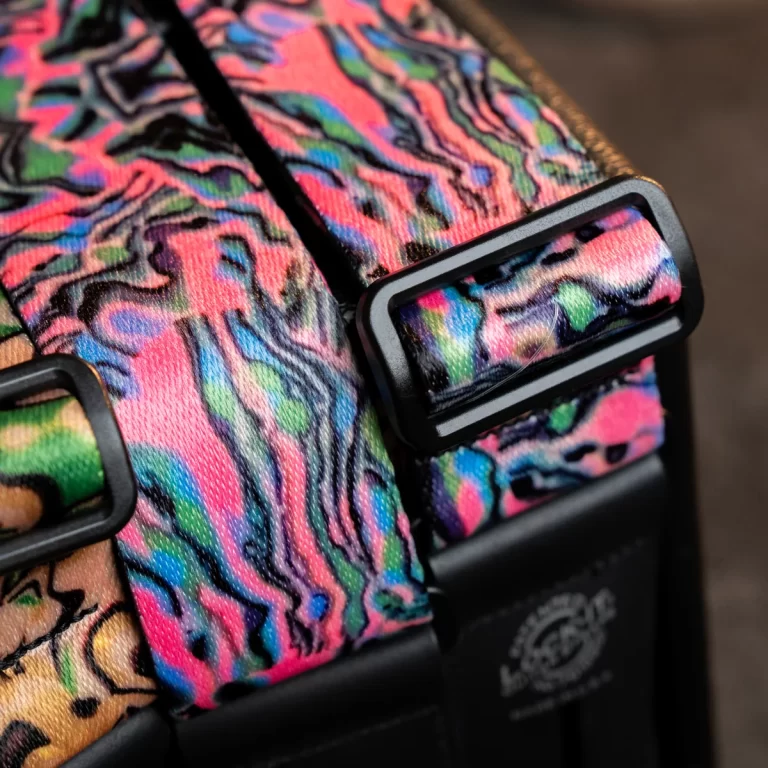 Close-up of a multicolor patterned fabric strap with a black plastic buckle on a bag ขายราคาพิเศษ