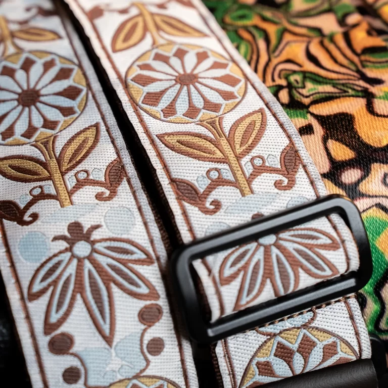 Close-up of a decorative fabric strap with brown, tan, and pale blue floral patterns and a black buckle. ขายราคาพิเศษ