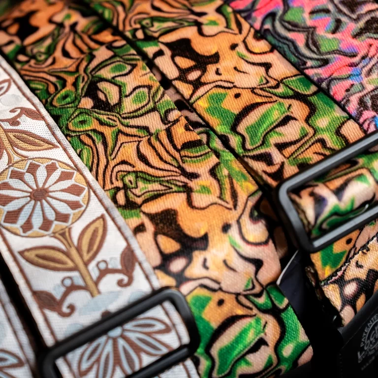 Close-up of colorful patterned fabric straps with black buckles, featuring orange-green jungle print and floral designs on the edges. ขายราคาพิเศษ