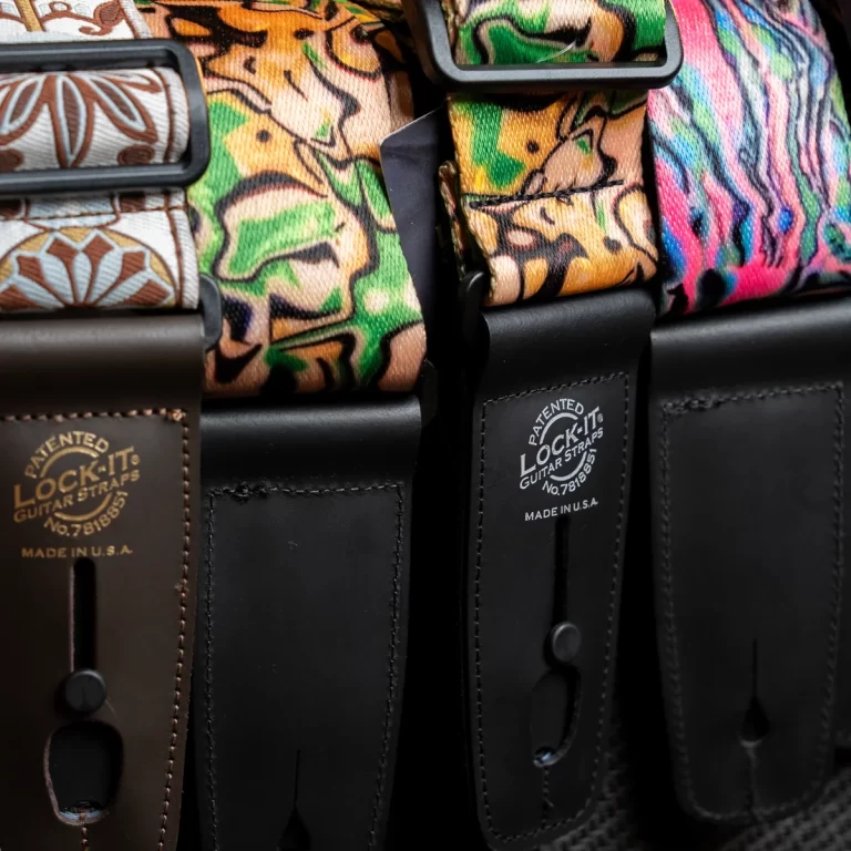 Close-up of colorful fabric guitar straps with leather ends and Lock-It branding... ขายราคาพิเศษ